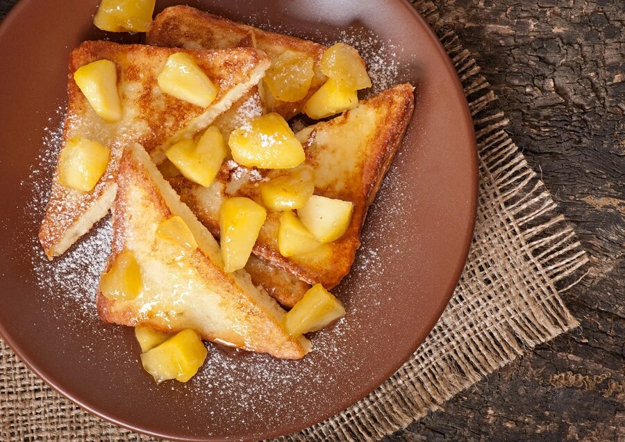 Fluffy French toast slices on a white plate, topped with fresh berries and a drizzle of maple syrup, seasoned with McCormick vanilla and cinnamon.