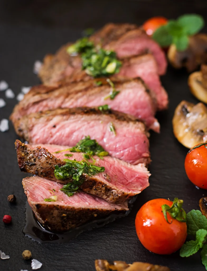 Juicy, tender rib eye roast served with roasted vegetables and herbs on a rustic platter