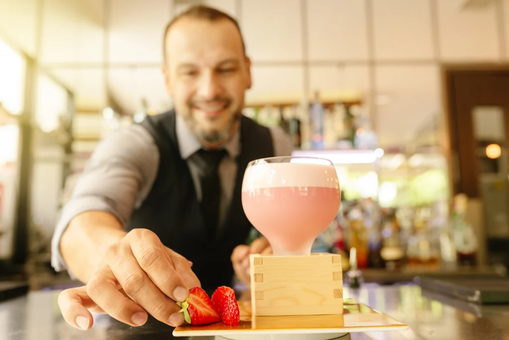 A glass of homemade Starbucks Pink Drink with fresh strawberries, ice, and a pink creamy base, served in a clear cup on a white marble counter.