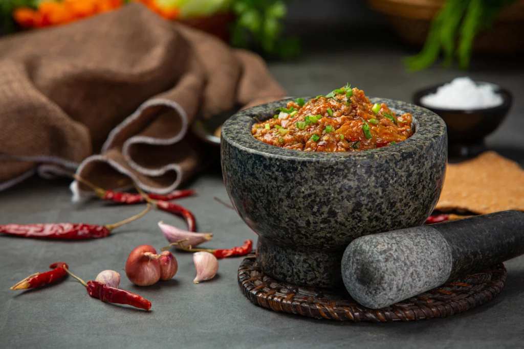 Jar of homemade salsa macha with dried chilies, garlic, peanuts, and oil on a rustic table