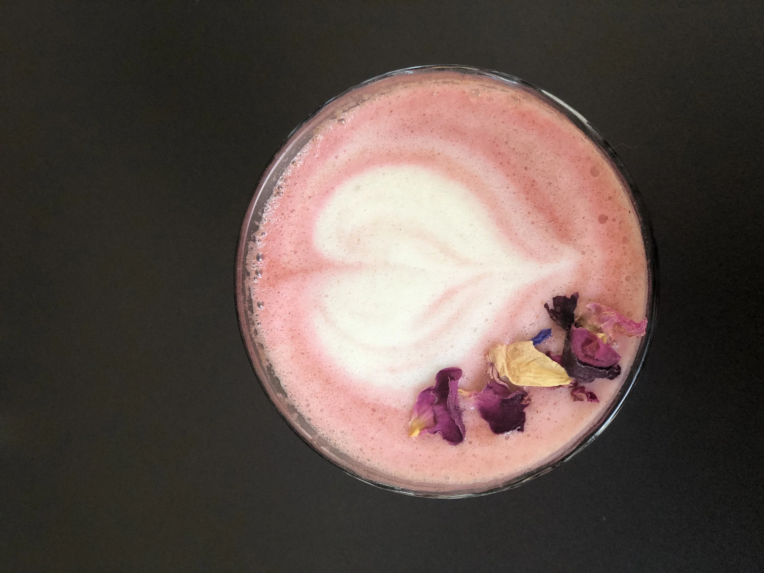 A glass of homemade Starbucks Pink Drink with fresh strawberries, ice, and a pink creamy base, served in a clear cup on a white marble counter