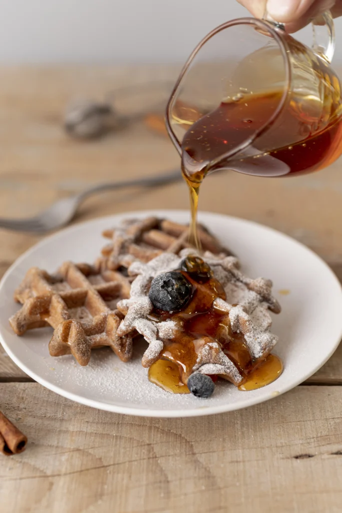 Golden brown Krusteaz waffles stacked on a plate with fresh berries and maple syrup