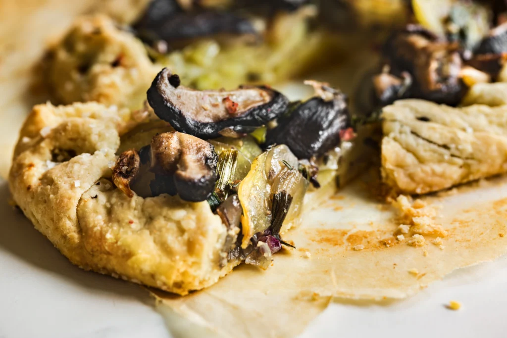 Crispy bacon savoury tart garnished with fresh herbs on a wooden board