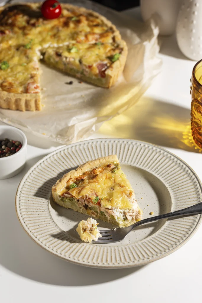 Crispy bacon savoury tart garnished with fresh herbs on a wooden board