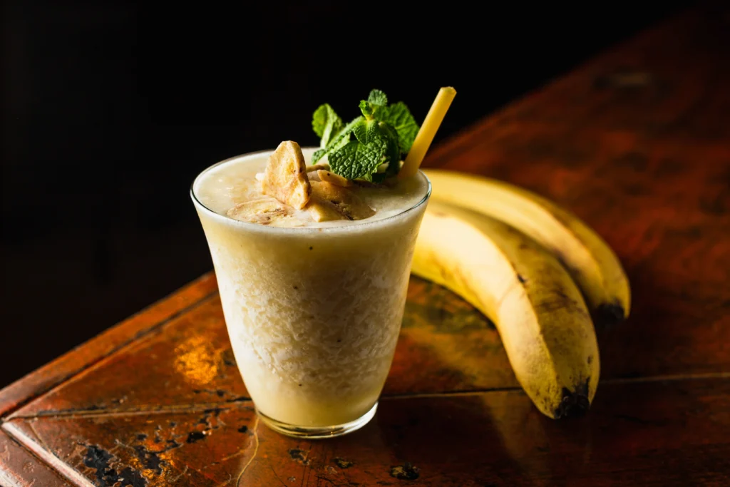 Iced banana coffee drink in a tall glass with a straw and banana slices garnish