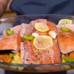 Oven-baked King salmon fillets with lemon, dill, and parsley on a white ceramic plate
