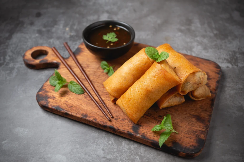 Crispy homemade veggie egg rolls filled with cabbage, carrots, and green onions, served with dipping sauce.