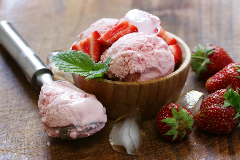 Homemade strawberries and cream ice cream in a bowl with fresh strawberries on top