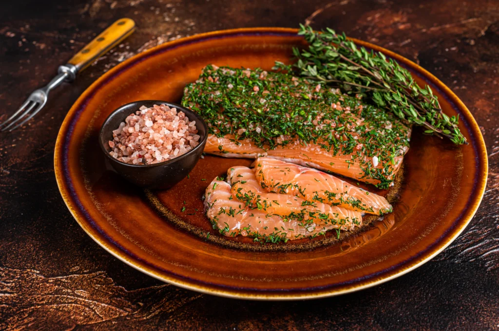 Oven-baked King salmon fillets with lemon, dill, and parsley on a white ceramic plate