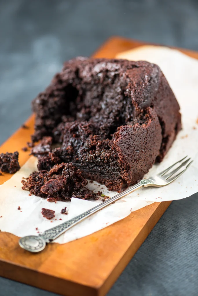 Slice of moist one-bowl chocolate cake with chocolate frosting on a white plate