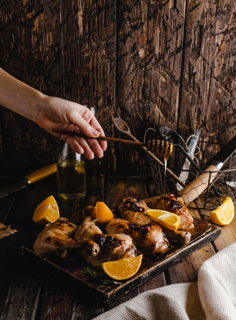 Golden-brown grilled lemonade chicken with charred grill marks and fresh lemon wedges on a platter.