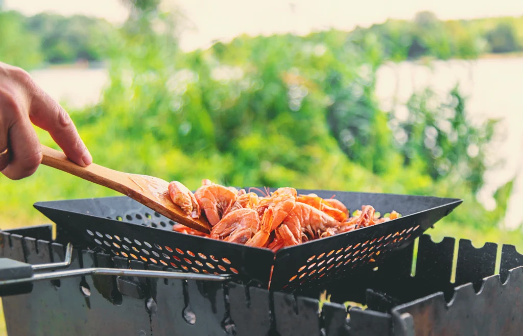 A close-up shot of a shrimp boil, featuring shrimp, corn, and potatoes, neatly arranged on a tray inside a red-and-white Igloo cooler. The cooler is lined with a checkered red-and-white cloth.