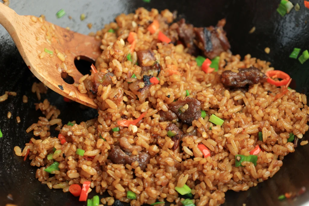 Step-by-step preparation of Blackstone fried rice on a flat top griddle with vegetables, eggs, and rice being stir-fried