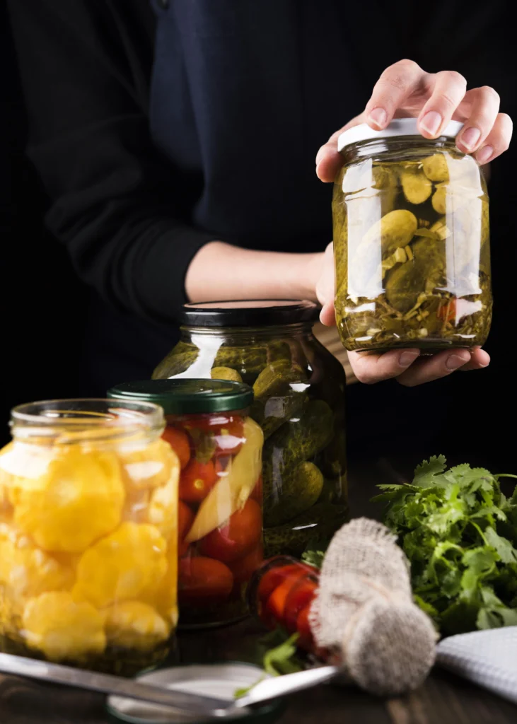 Homemade canned dill pickles in glass jars with fresh garlic and dill sprigs