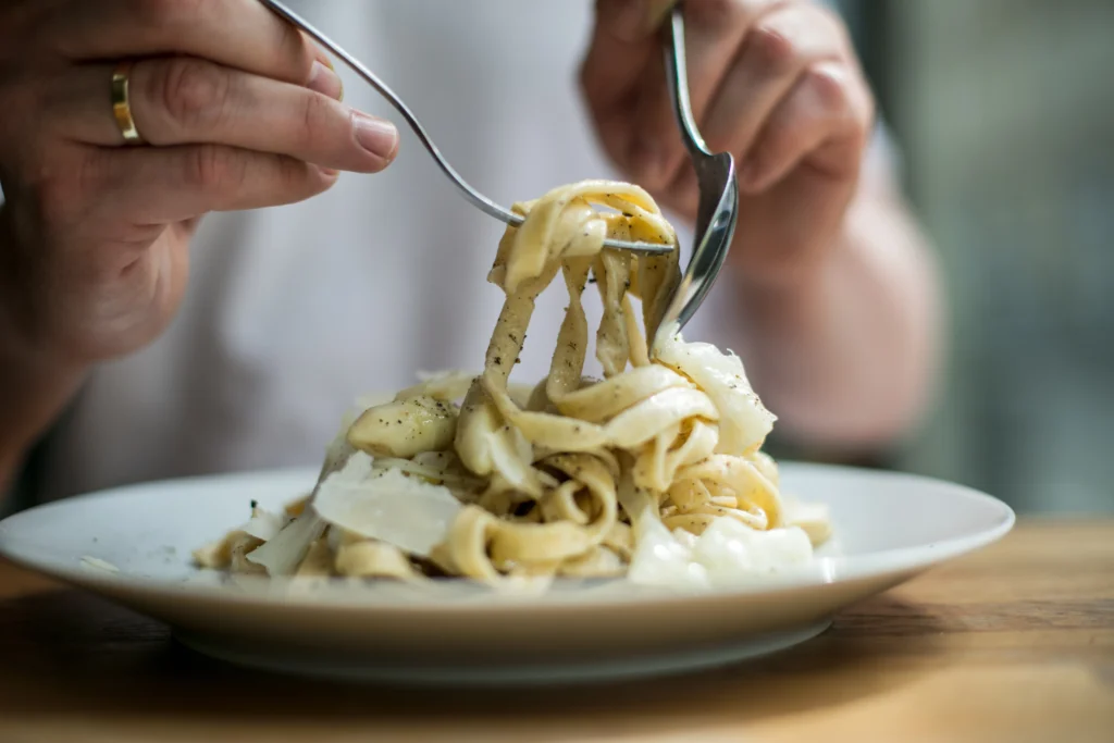A bowl of creamy Boursin cheese pasta topped with fresh herbs and served in a white dish.