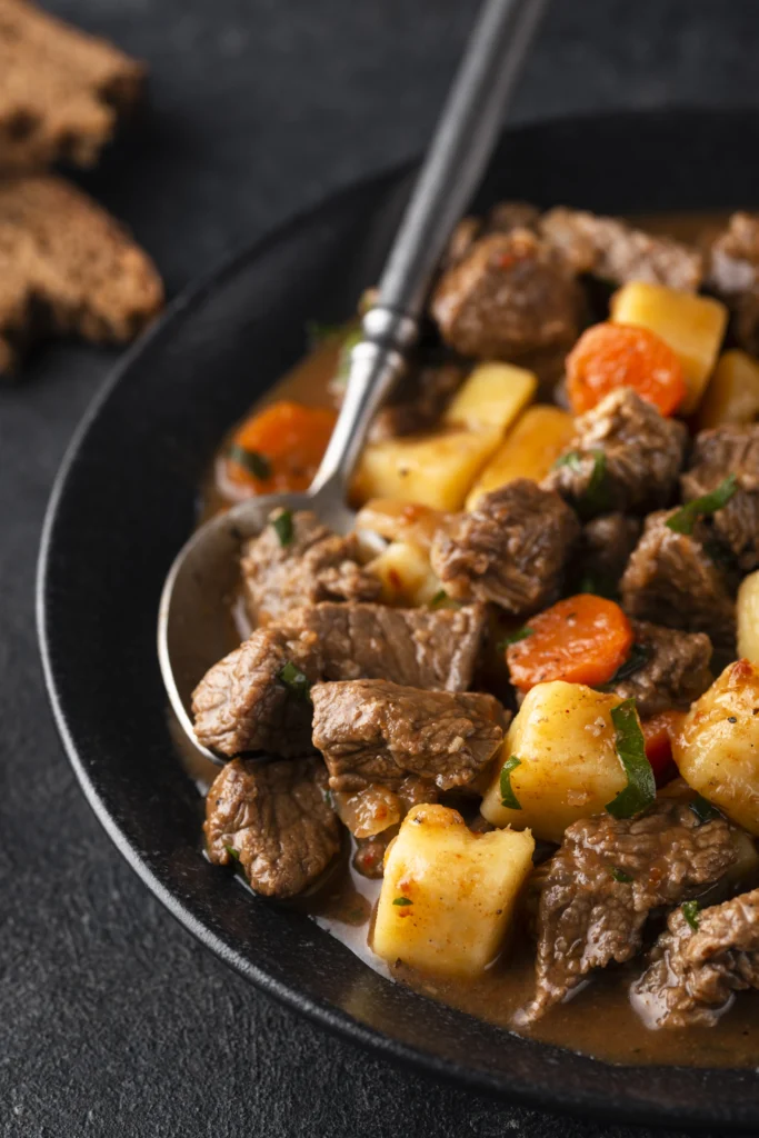 A bowl of Filipino Beef Caldereta with tender beef, vegetables, and rich tomato sauce, served with steamed rice