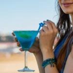 Blue Margarita cocktail in a glass with a lime wedge and blueberries, garnished with a salt rim, served on a summer night
