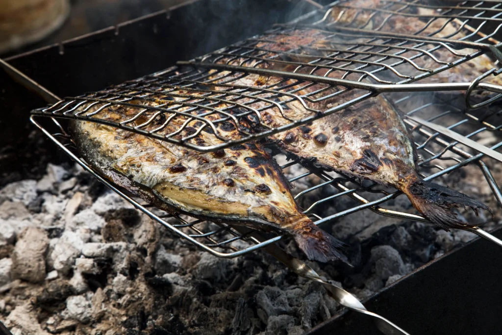 Grilled branzino fillet with garlic, olive oil, and lemon slices on a serving platter.