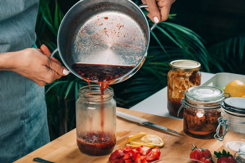 Homemade strawberry preserves in glass jars with fresh strawberries on a wooden table