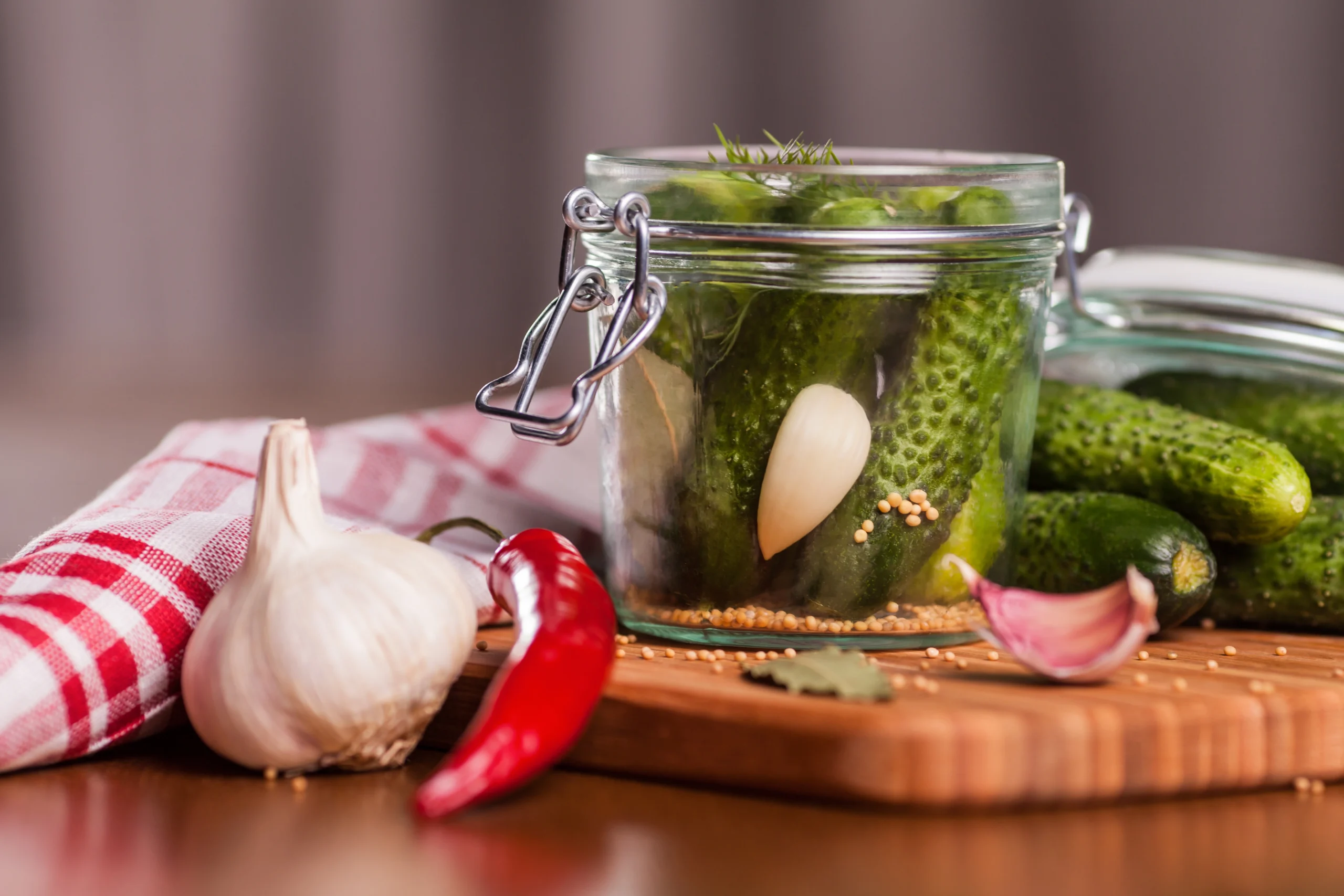Homemade canned dill pickles in glass jars with fresh garlic and dill sprigs