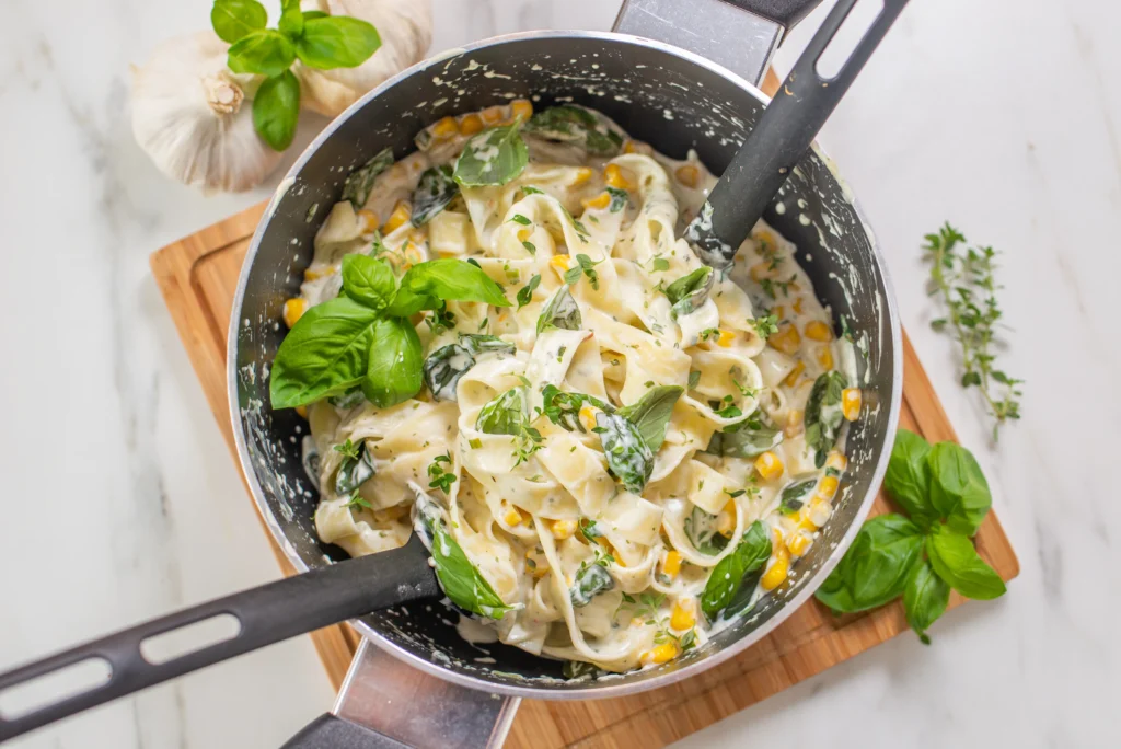 A bowl of creamy Boursin cheese pasta topped with fresh herbs and served in a white dish.