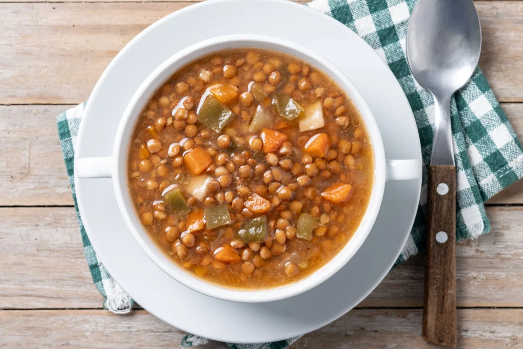 A hearty vegetarian crockpot meal with fresh vegetables, beans, and herbs simmering in a slow cooker.