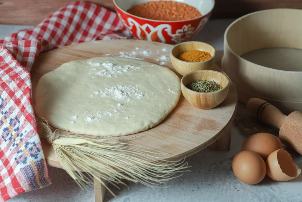 Homemade thin crust pizza dough rolled out on a floured surface, ready for baking.