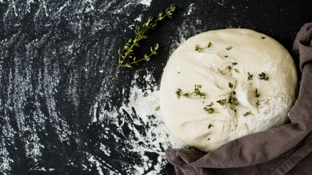 Homemade thin crust pizza dough rolled out on a floured surface, ready for baking.