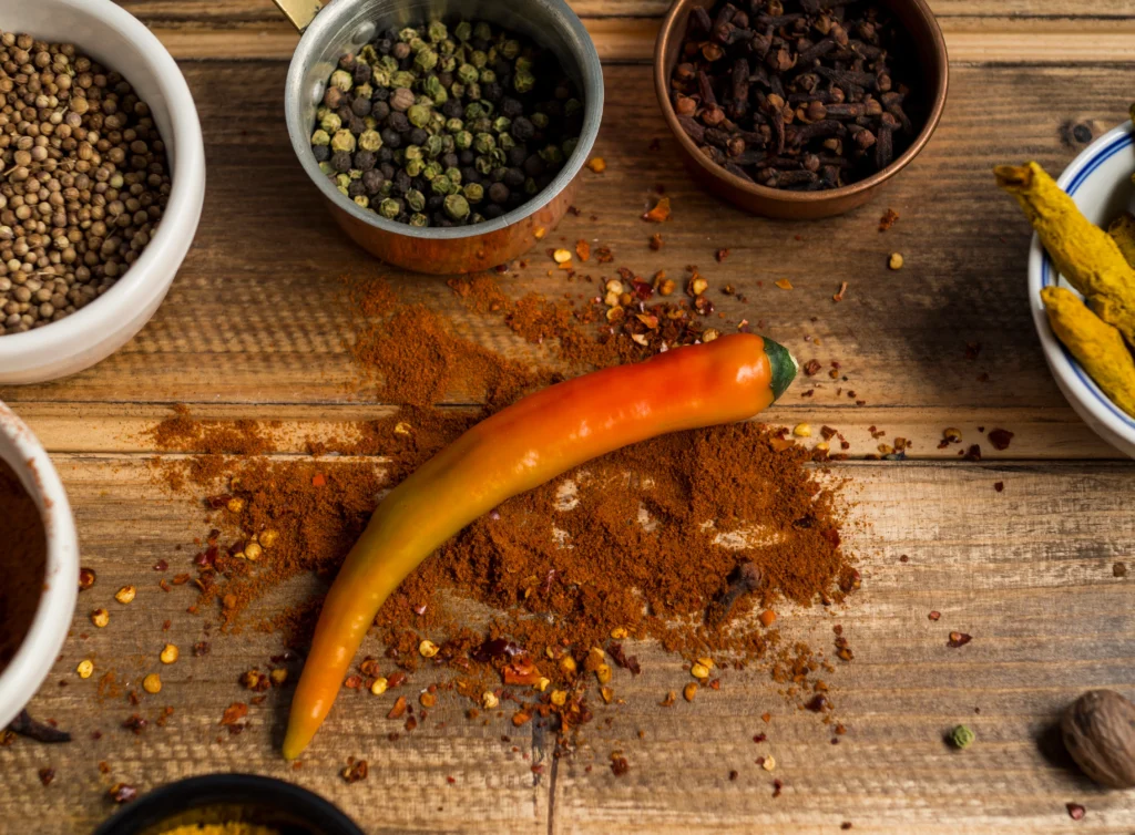 A bowl of homemade smoky chili seasoning blend with paprika, cumin, and chili powder on a rustic wooden table.
