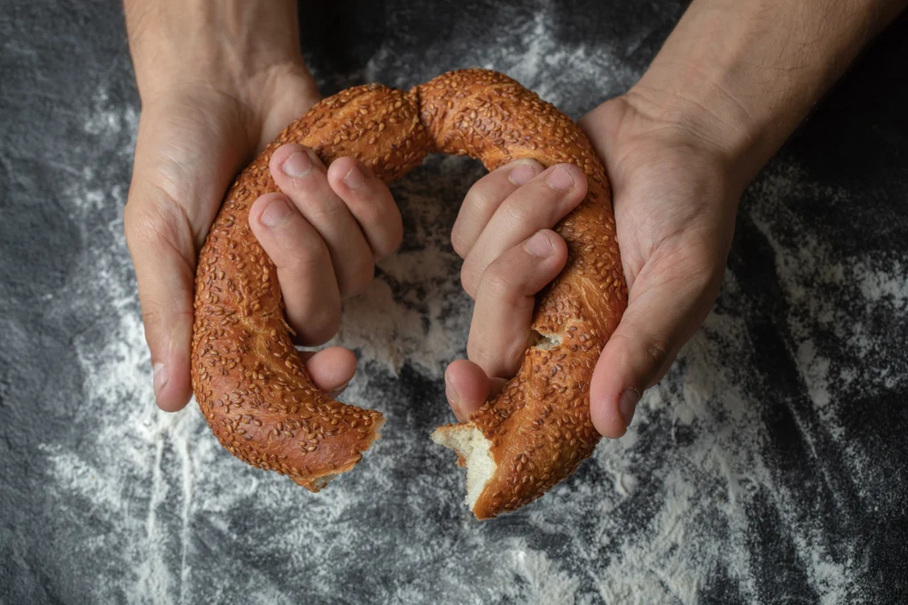 Freshly baked homemade bagels cooling on a wire rack, with cream cheese on the side.