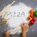 Homemade thin crust pizza dough rolled out on a floured surface, ready for baking.