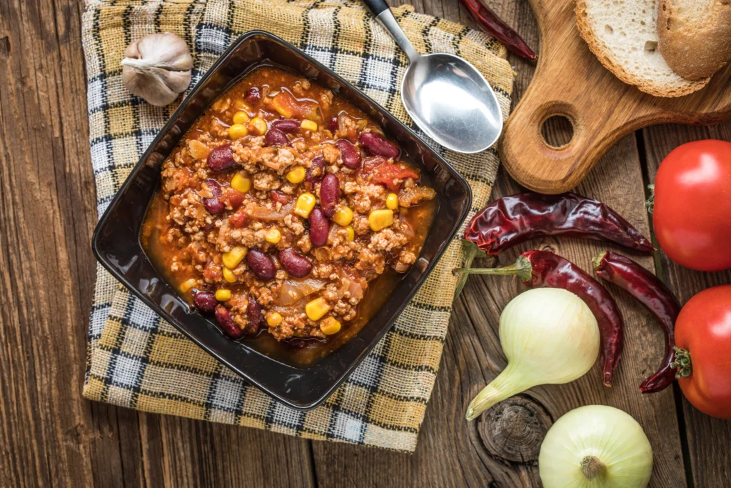 Bowl of award-winning crockpot chili topped with shredded cheese, sour cream, and fresh herbs