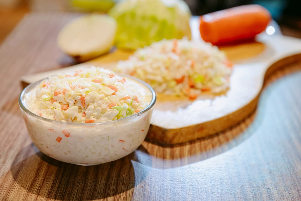 A bowl of creamy KFC coleslaw with finely chopped cabbage and carrots in a tangy dressing, served as a side dish for any meal.