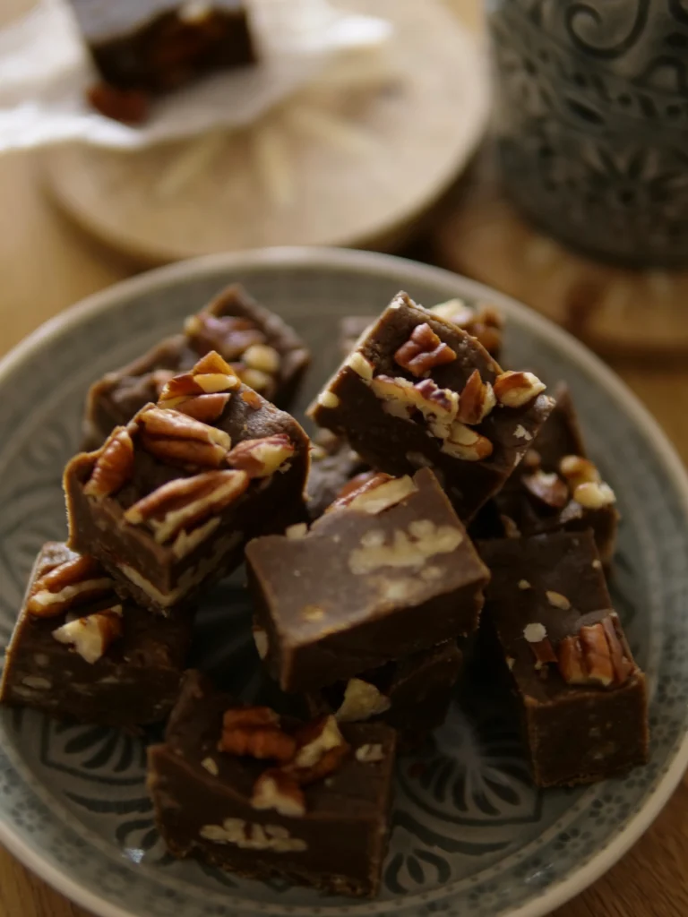 Quick and Magical Fantasy Fudge squares topped with walnuts on a wooden board.