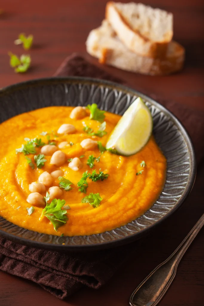 Creamy butternut squash and chickpea soup served in a bowl, garnished with fresh herbs