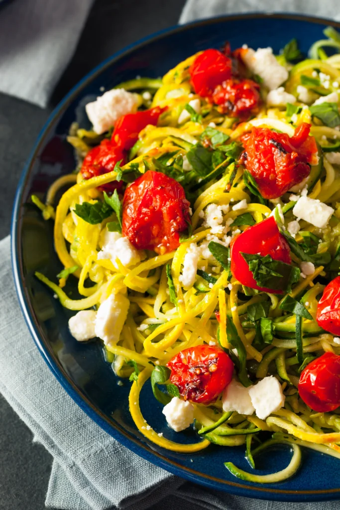 Zucchini Pasta with Cherry Tomatoes and Pesto
Zucchini noodles tossed with cherry tomatoes and green pesto, served in a white bowl.