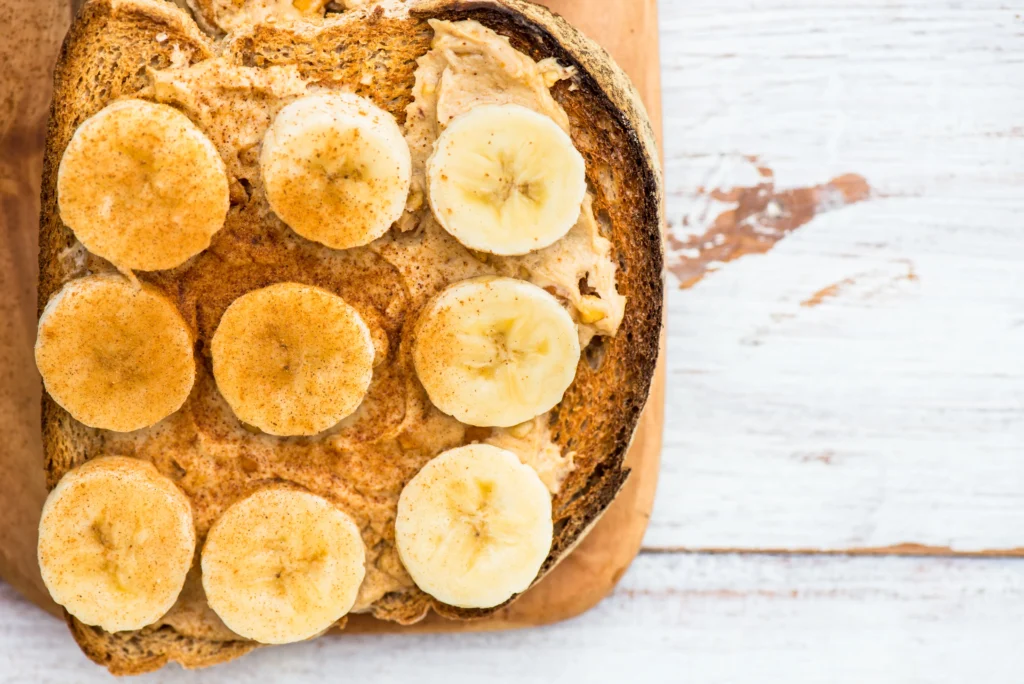 Slice of banana almond butter toast with banana slices, almond butter spread, and whole grain bread