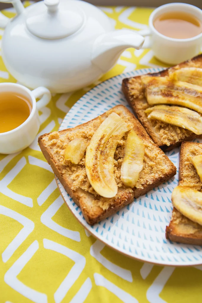 Slice of banana almond butter toast with banana slices, almond butter spread, and whole grain bread