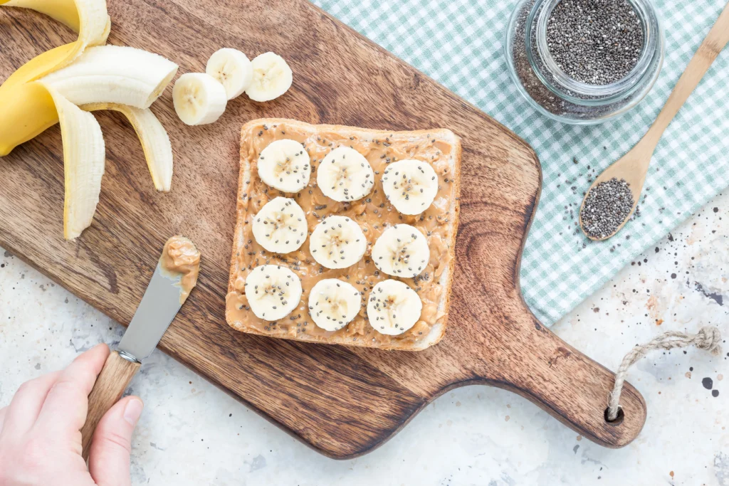 Slice of banana almond butter toast with banana slices, almond butter spread, and whole grain bread
