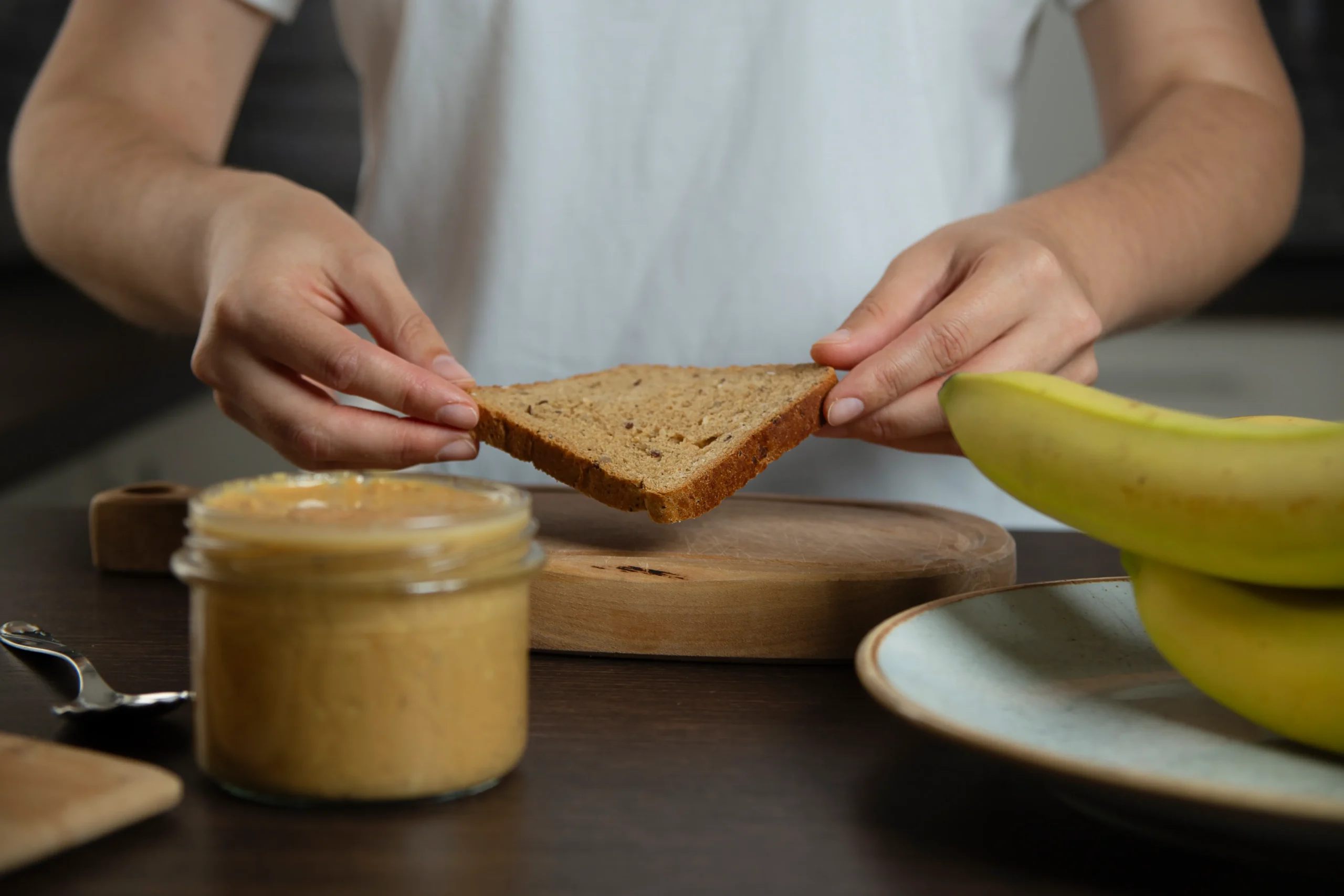Slice of banana almond butter toast with banana slices, almond butter spread, and whole grain bread
