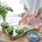 Almond chicken glazed with honey sauce, garnished with toasted almonds and fresh herbs on a white plate.