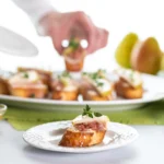 Golden Goat Cheese & Honey Crostini topped with flaky sea salt and fresh thyme on toasted baguette slices.