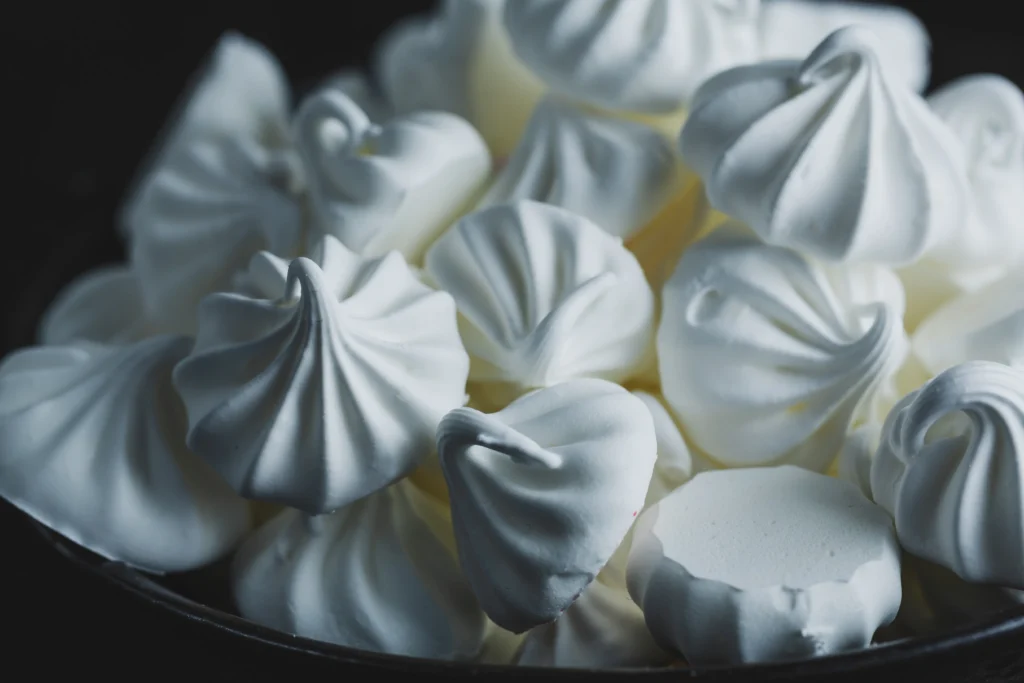 Perfect meringue with glossy stiff peaks whipped in a clean mixing bowl, ready for baking