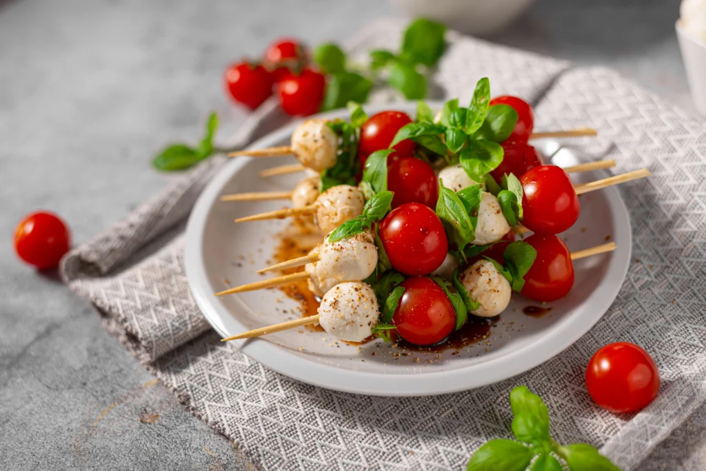 Heart-themed Valentine’s Day mini Caprese skewers with cherry tomatoes, mozzarella balls, and fresh basil arranged on a festive platter