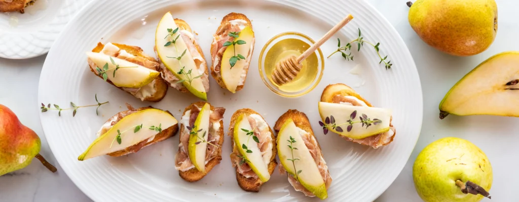Golden Goat Cheese & Honey Crostini topped with flaky sea salt and fresh thyme on toasted baguette slices.