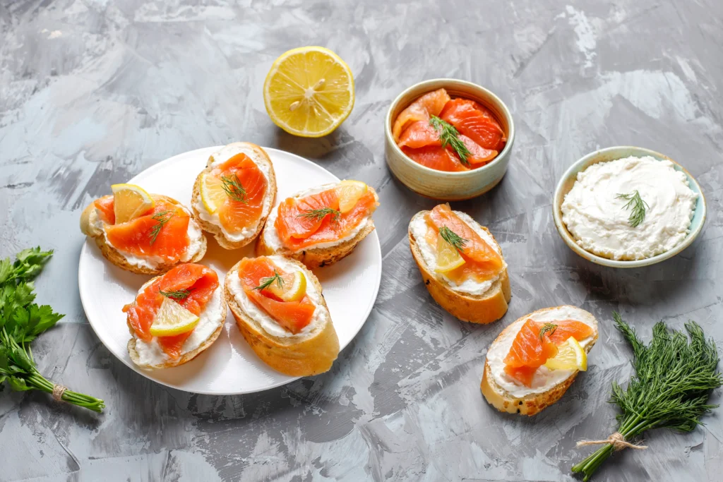 Smoked salmon crostini topped with fresh dill and capers on a bed of herb-infused cream cheese and toasted baguette slices.