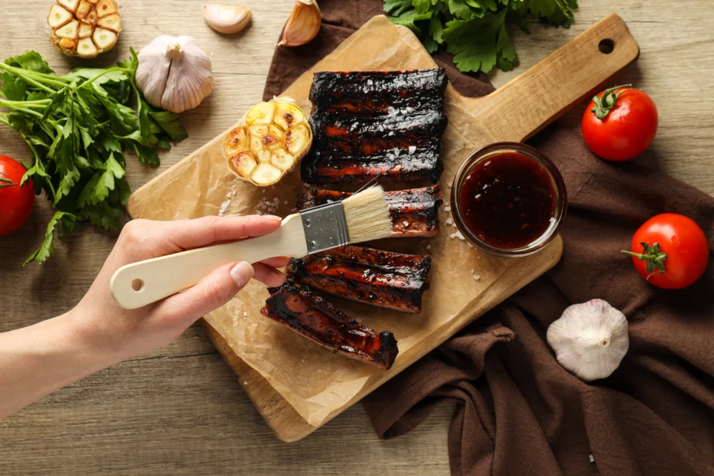Spicy rib rub seasoning blend being sprinkled over raw pork ribs before grilling