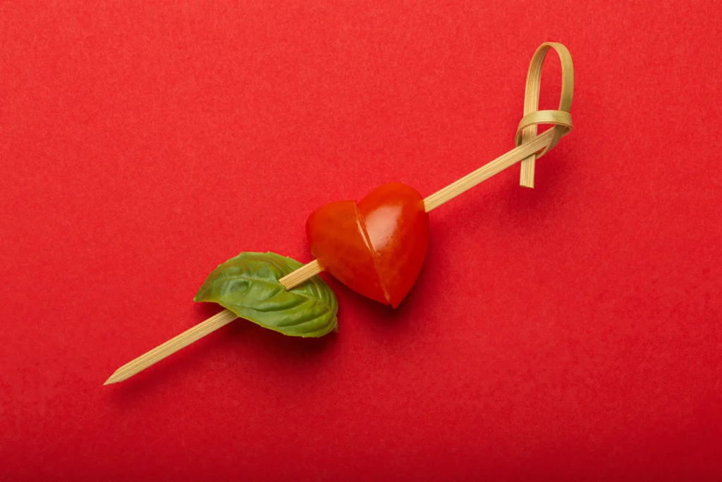 Heart-themed Valentine’s Day mini Caprese skewers with cherry tomatoes, mozzarella balls, and fresh basil arranged on a festive platter