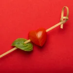 Heart-themed Valentine’s Day mini Caprese skewers with cherry tomatoes, mozzarella balls, and fresh basil arranged on a festive platter
