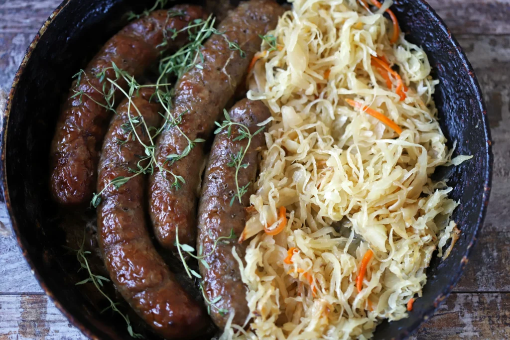 German-style bratwurst served with sauerkraut on a rustic plate, traditional sausage recipe with mustard and herbs